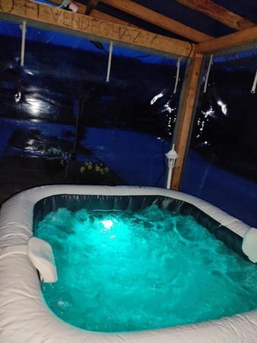 a jacuzzi tub in a tent with blue water at Szofi Vendégház in Kereki