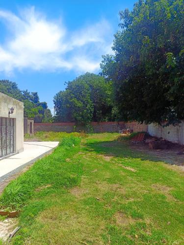 a grassy yard with a fence and a tree at Rio Holístico cuádruple Agua in Ramallo