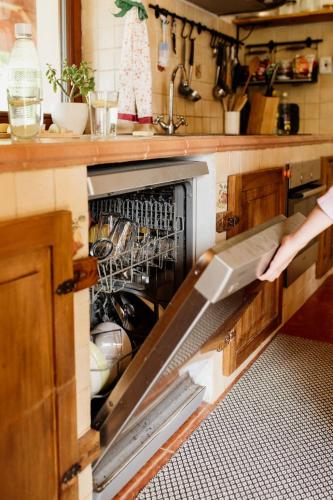 a person reaching into an open dishwasher in a kitchen at Chata Hana Donovaly in Donovaly