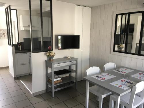 une cuisine avec une table, une télévision, une table et des chaises dans l'établissement Belle maison dans résidence avec piscine, à La Flotte