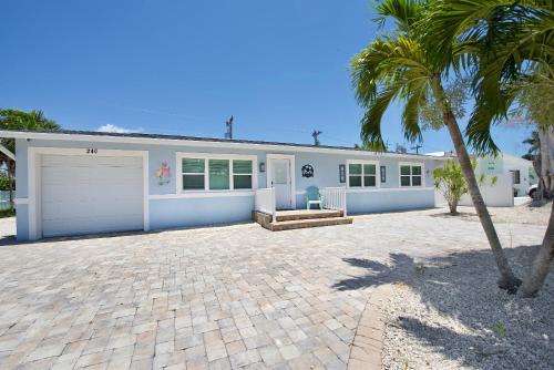 a house with a garage and a palm tree at Ocean Breeze by Sun Palace Vacations in Fort Myers Beach