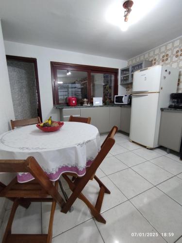a kitchen with a table and chairs and a white refrigerator at Sobrado terreo aconchegante in Capão da Canoa