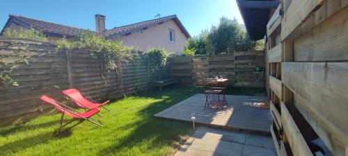 une cour avec deux chaises, une table et une clôture dans l'établissement A 10 minutes des plus belles plages landaises, charmant T2 avec jardin privatif, à Angresse