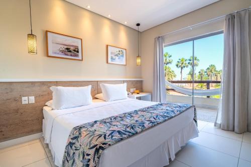 a bedroom with a large bed and a large window at Cana Brava All Inclusive Resort in Ilhéus