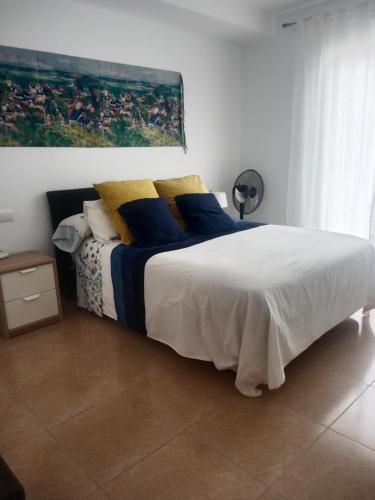 a bedroom with a large bed with blue and yellow pillows at Sol y playa in Palomares