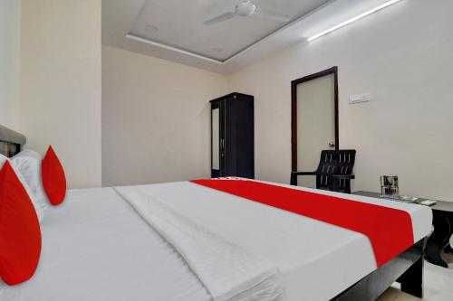 a bedroom with a large white bed with red accents at Hotel O Shri Ganesh Near By Himayatnagar,Ashok Nagar,RTC X Roads in Hyderabad