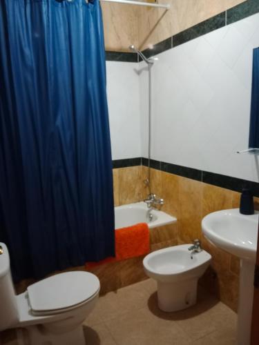 a bathroom with a blue shower curtain and a toilet and a sink at Sol y playa in Palomares
