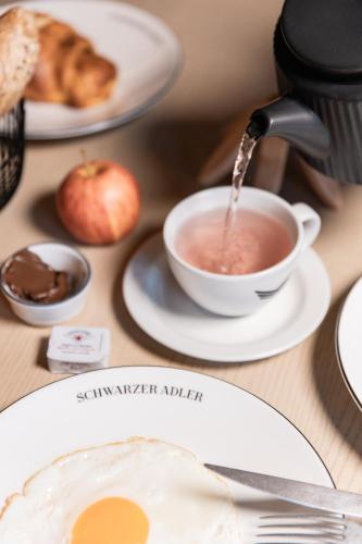 a cup of coffee and an apple on a table at Schwarzer Adler - Concept Living in Vipiteno