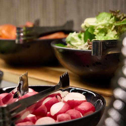 a bowl of radicans with tongs on a table with bowls of salad at Radisson Blu Hotel Zurich Airport in Kloten
