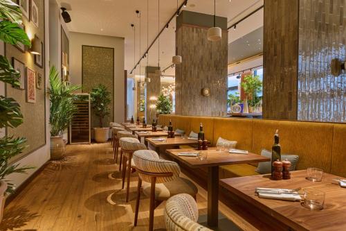 a restaurant with wooden tables and chairs and plants at Radisson Blu Hotel Zurich Airport in Kloten