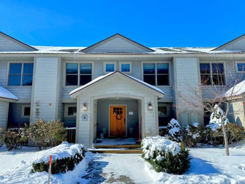 a white house with a door in the snow at H4 Ski Slope Views! Bretton Woods condo with easy access to Mt Washington, Skiing, White Mountains! in Carroll