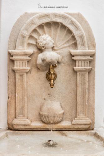 a statue of a water fountain on a wall at Schwarzer Adler - Concept Living in Vipiteno