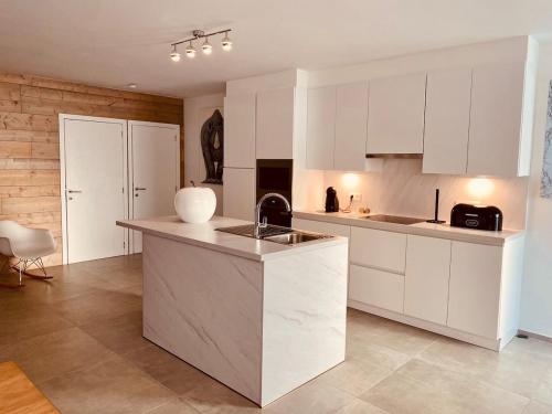 a kitchen with white cabinets and a sink at Loft de Waroux in Awans