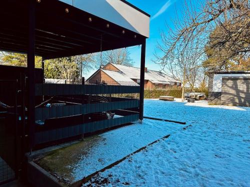 a fence with snow on the ground next to a house at Loft de Waroux in Awans