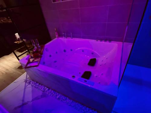 a pink bath tub in a room with purple lights at Loft de Waroux in Awans