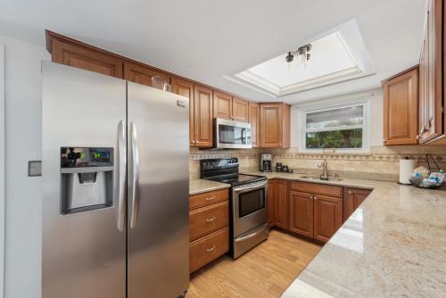 a kitchen with wooden cabinets and a stainless steel refrigerator at Beach Bungalow by Sun Palace Vacations in Fort Myers Beach