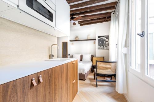 - une cuisine avec évier et un lit dans une chambre dans l'établissement Montmorency - Studio unique, à Paris