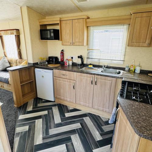 a kitchen with wooden cabinets and a geometric floor at Summer Dreams Holiday Home Skegness in Skegness