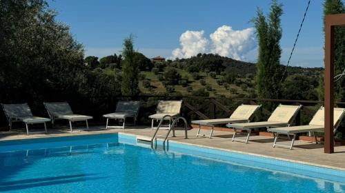 a pool with lounge chairs and a view of a mountain at Madonna Del Poggio CAV in Scarlino