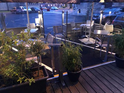 a patio with chairs and tables and plants at Hôtel - Restaurant Au Tonnelier in Bergues