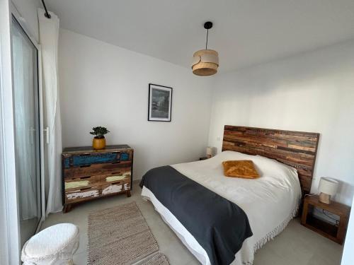 une chambre avec un grand lit avec une tête de lit en bois dans l'établissement SEJOUR DE CHARME A CALVI vue mer et montagne en T3 résidentiel avec piscine, à Calvi