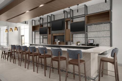a bar with a row of stools in a room at Hilton Garden Inn Denver Airport Tower Road in Denver