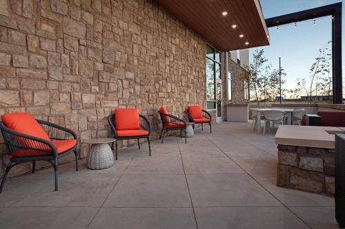 a patio with chairs and tables and a stone wall at Hilton Garden Inn Denver Airport Tower Road in Denver