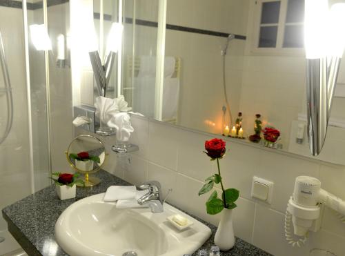 a bathroom with a sink and a mirror and red roses at Hotel BEI SCHUMANN in Kirschau