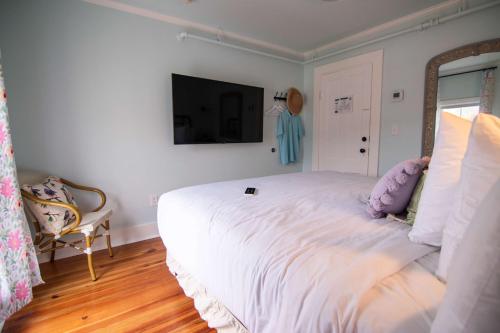 a bedroom with a large white bed with a television on the wall at Ocean House Boutique Hotel & Motel in Old Orchard Beach