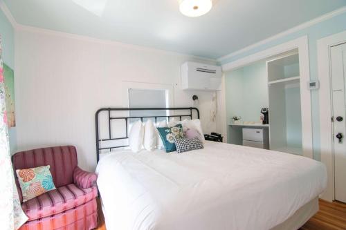 a bedroom with a white bed and a pink chair at Ocean House Boutique Hotel & Motel in Old Orchard Beach