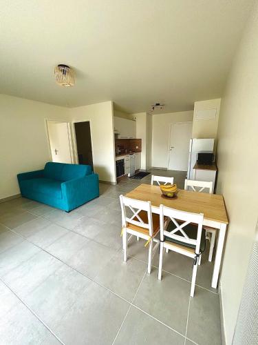 un salon avec une table et un canapé bleu dans l'établissement Appartement au bord de la plage et de la foret, à Mimizan-Plage