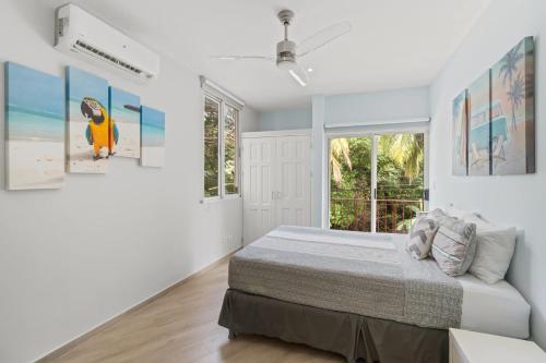 a white bedroom with a bed and a window at Newly Renovated Beachfront Condo with Inviting Minimalist Design, Pool & Balcony with Ocean Views in Playa Flamingo