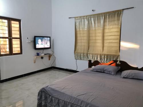 a bedroom with a large bed and a television at Sengo House in Jomba