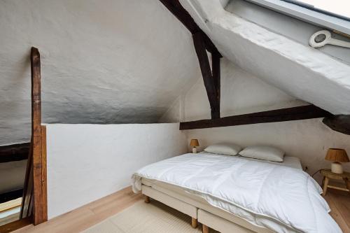 une chambre avec un lit blanc dans un grenier dans l'établissement Le condorcet, à Dijon