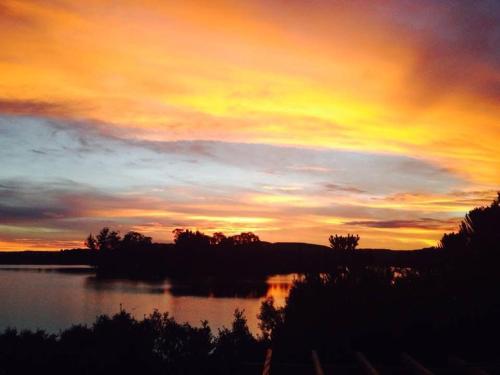 a sunset over a body of water with trees and clouds at Paraíso do Salto in Lages