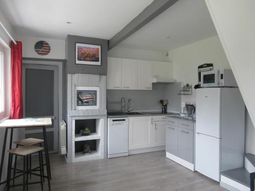 une cuisine avec des armoires blanches et un réfrigérateur blanc dans l'établissement La petite maison proche Étretat, à Beaurepaire