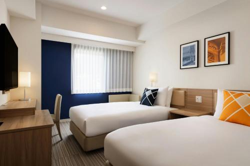a hotel room with two beds and a television at Four Points Flex by Sheraton Kobe Sannomiya in Kobe