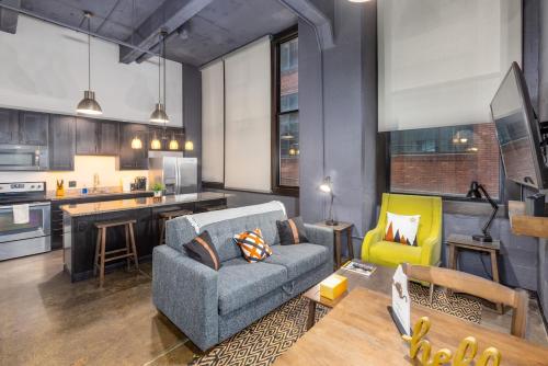 a living room with a couch and a kitchen at King Bed - Heart of PB - Jaw-Dropping Rooftop and Gym in Pittsburgh