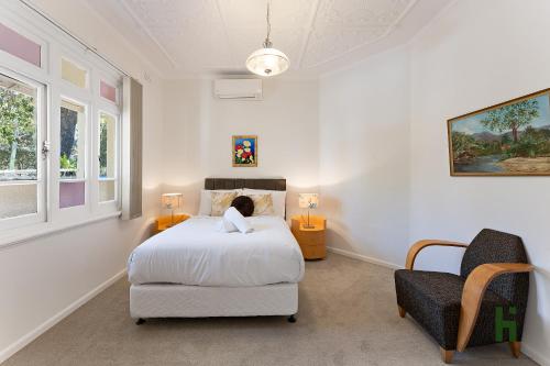 a white bedroom with a bed and a chair at edgeware house in Sydney