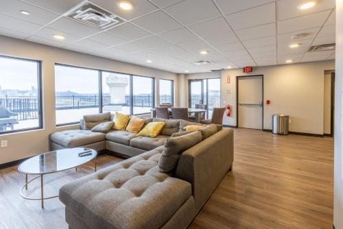 a living room with couches and a table and windows at King Bed - Heart of PB - Jaw-Dropping Rooftop and Gym in Pittsburgh