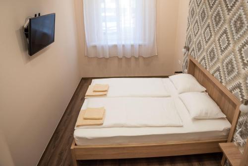 a small bed in a room with a tv at Gesztenye Apartman in Makó