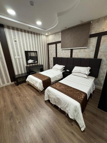 a hotel room with two beds and a television at Oroub El Forssan in Buraydah