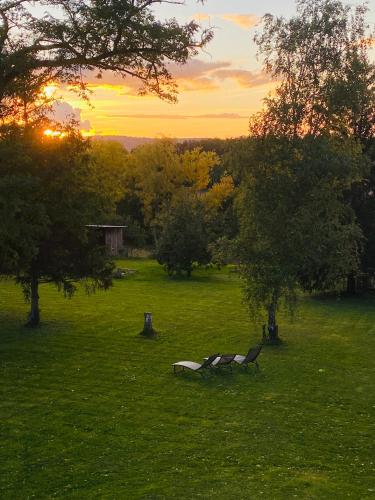 two benches in a field with the sunset in the background at La Maison de l'Andelot in Monteignet-sur-lʼAndelot