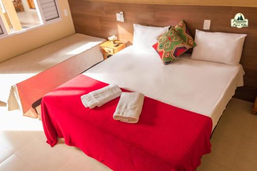 a bedroom with a large white bed with red blanket at Pousada Canastra Pai e Filho in São João Batista do Glória