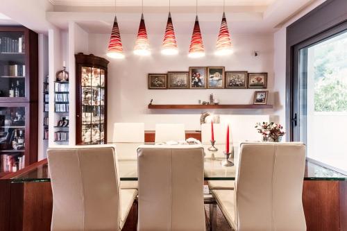 a dining room with a table with chairs and candles at Superb Athens Airport Residence, Unique View in Spáta