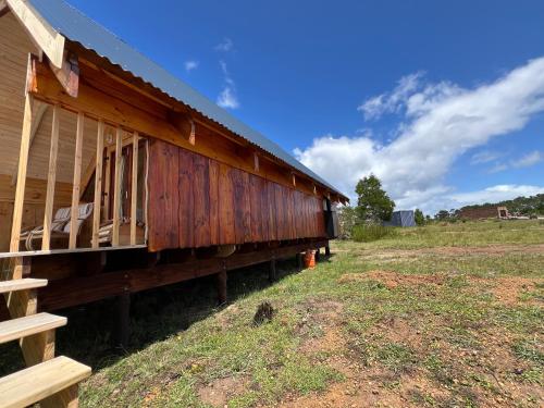 a wooden building sitting on the side of a field at Plett Yellowwood Tiny House in Plettenbergbaai