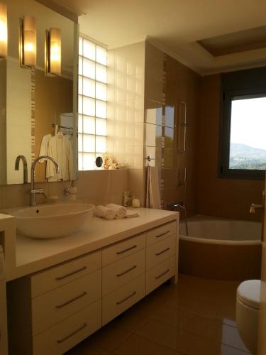 a bathroom with a sink and a tub and a toilet at Superb Athens Airport Residence, Unique View in Spáta
