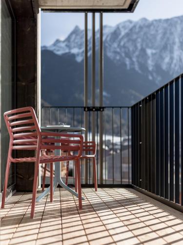 a table and a chair on a balcony with mountains at Aparthotel Tante Trude in Oetz