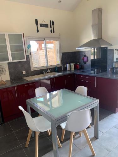 une cuisine avec une table en verre et des chaises blanches dans l'établissement Aux Agréous, à Jû-Belloc