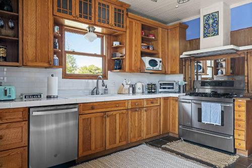 a kitchen with wooden cabinets and stainless steel appliances at Kingsby Farmhouse - 1BR with 2 Queens & Mountain Views in Boerne